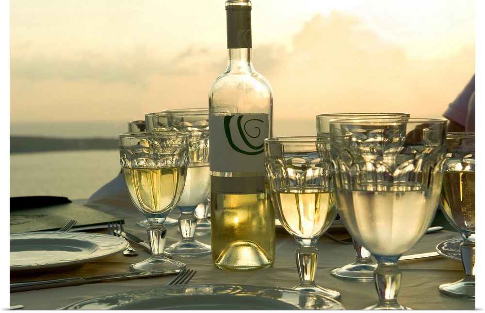 Horizontal photograph on a big wall hanging of place settings on a  table, surrounded by many full glasses of wine, the op...