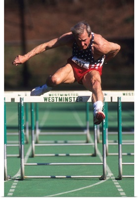 Elderly male track and field athlete hurdling