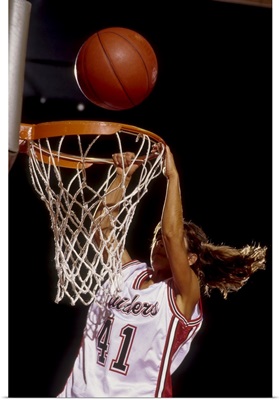Female basketball player slam dunking
