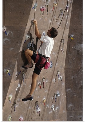 Man wall climbing indoors with equipment