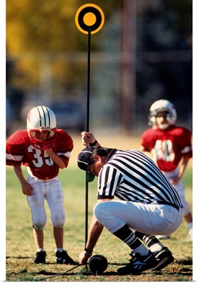 Referee measuring for a first down during a pee wee football game