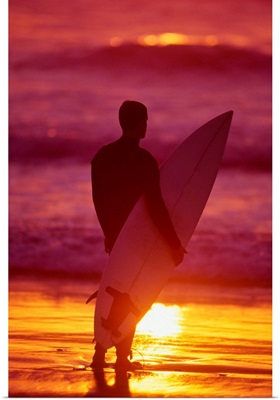 Surfer watching ocean sunset