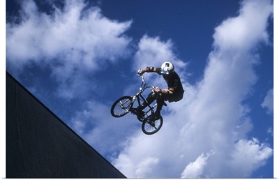 Teenage boy flies over the vert on a BMX bike