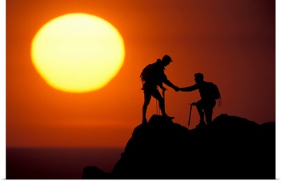 Two climbers reach the summit at sunrise