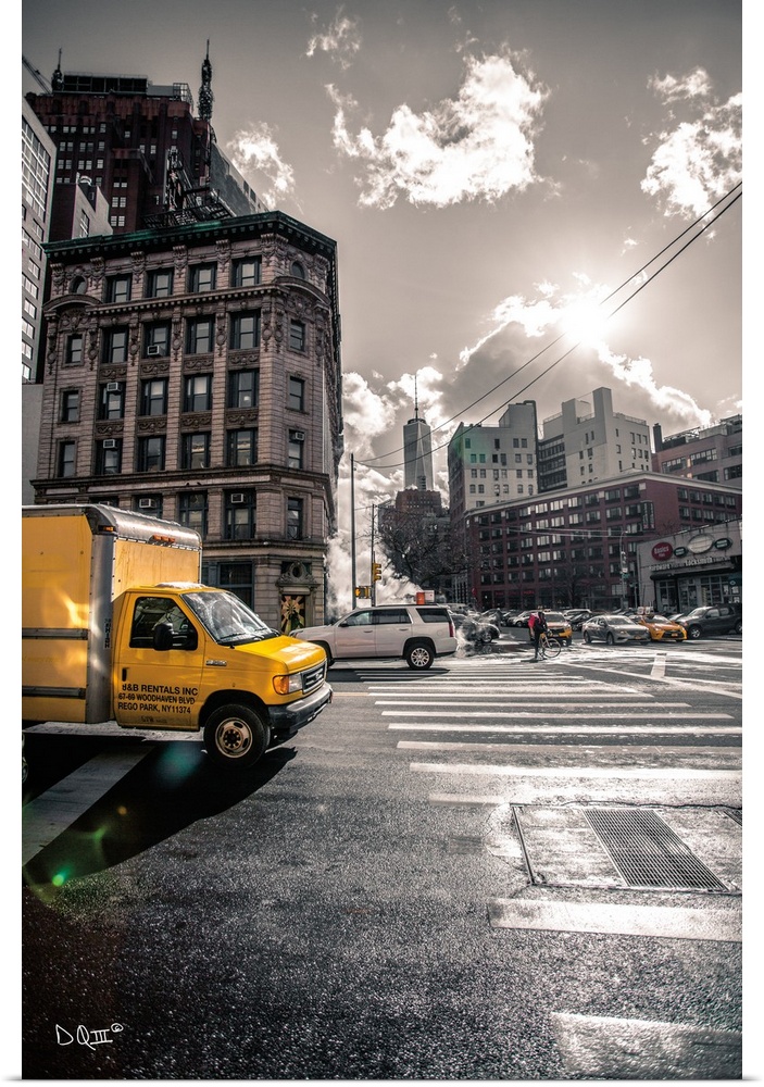 Photograph of a yellow truck popping against a subdued city street scene.