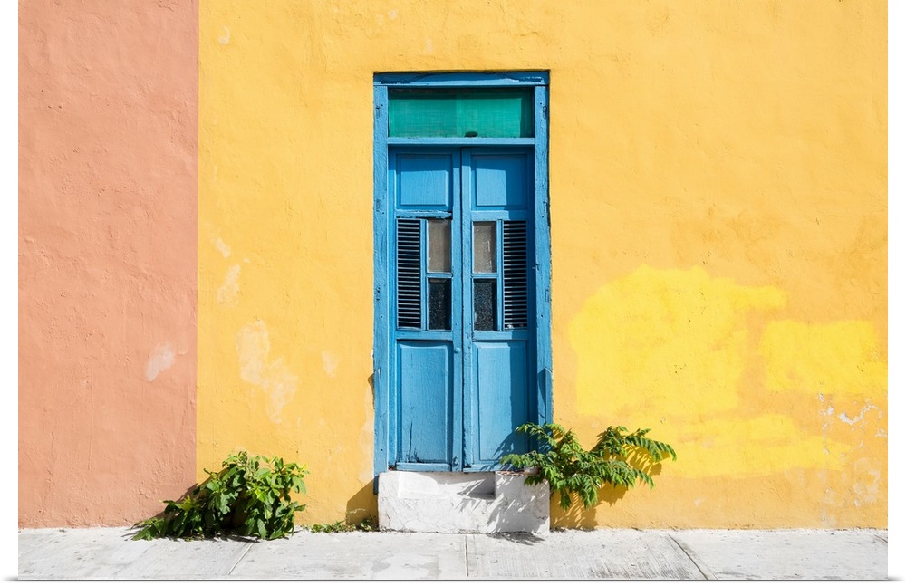 Photograph of a pale yellow and pink exterior wall with a bright blue door off the street in Mexico. From the Viva Mexico ...