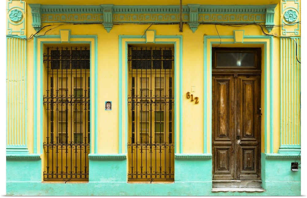 Photograph of a turquoise and yellow building facade with two windows and a wooden door in Havana, Cuba