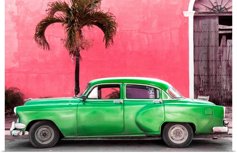 Photograph of a green vintage car parked outside of a bright pink building with a palm tree.