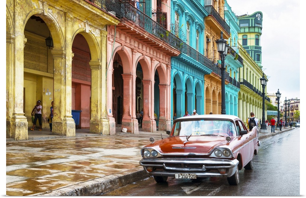 Photograph of a red vintage car parked outside of a colorful building facade in Havana, Cuba.