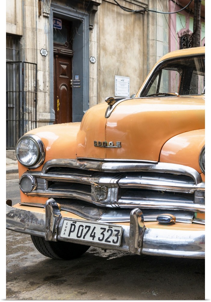 Photograph of the front of an orange vintage Dodge car parked in downtown Havana.