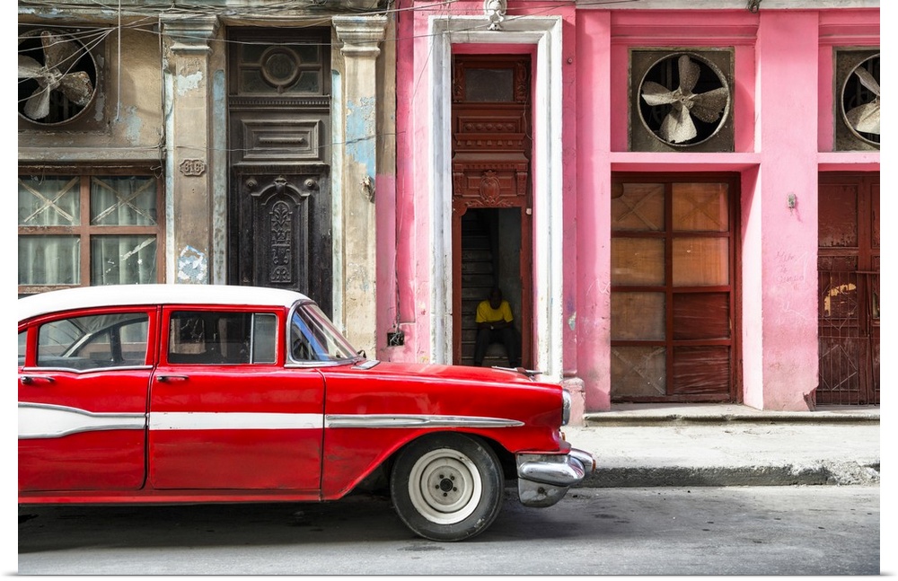 Photograph of a classic old red car in front of a pink facade in Havana, Cuba.