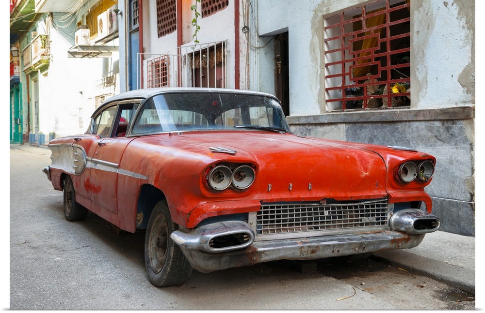 Photograph of an old beat up red car parked on the streets of Havana.