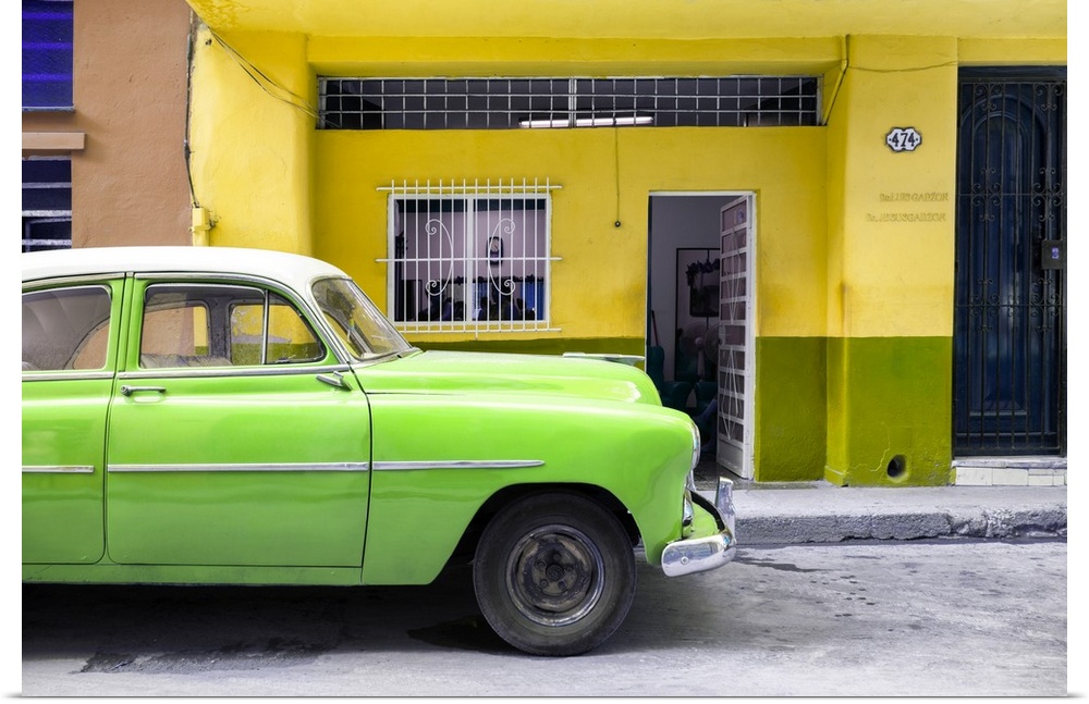 Photograph of a bright green vintage car parked on the road in Havana with a bright yellow facade in the background.
