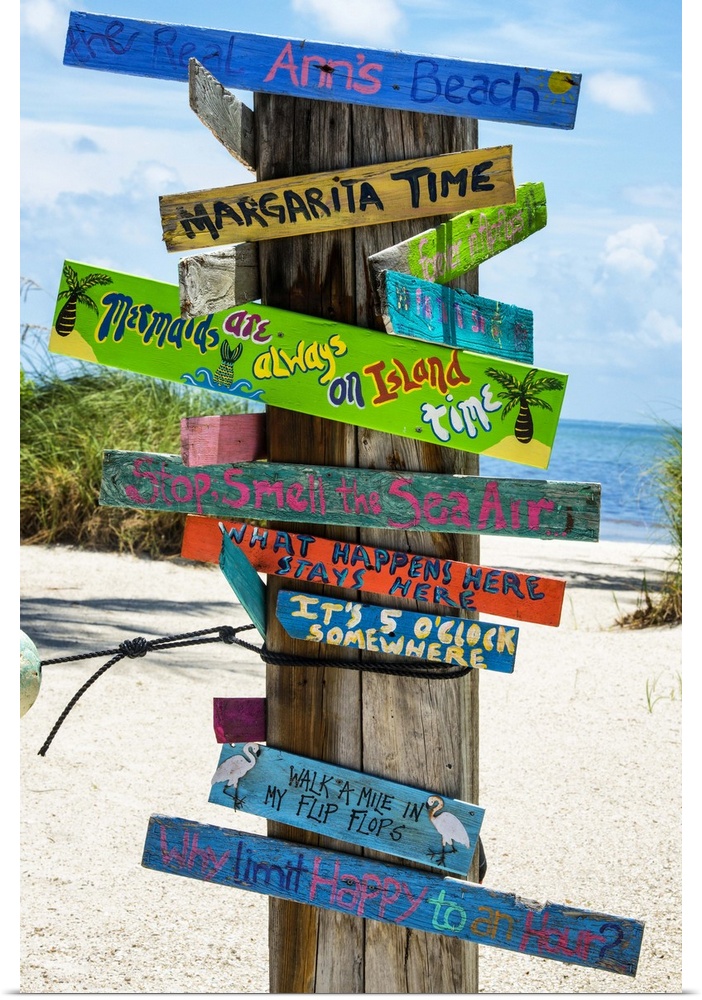 A collection of colorful humorous signs on a wooden post on the beach.