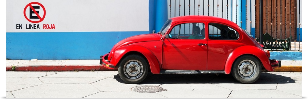 Panoramic photograph of a red Volkswagen Beetle parked in front of a building with blueand white walls. From the Viva Mexi...