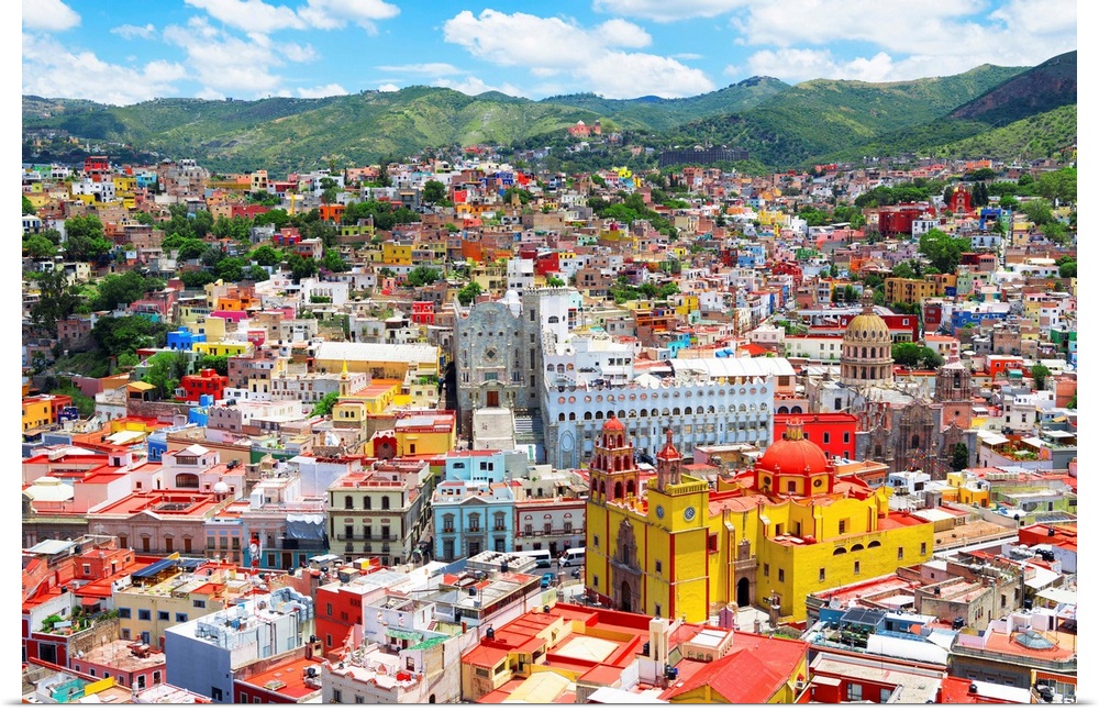 Aerial photograph of the city of Guanajuato, Mexico, with colorful buildings and mountains in the background. From the Viv...