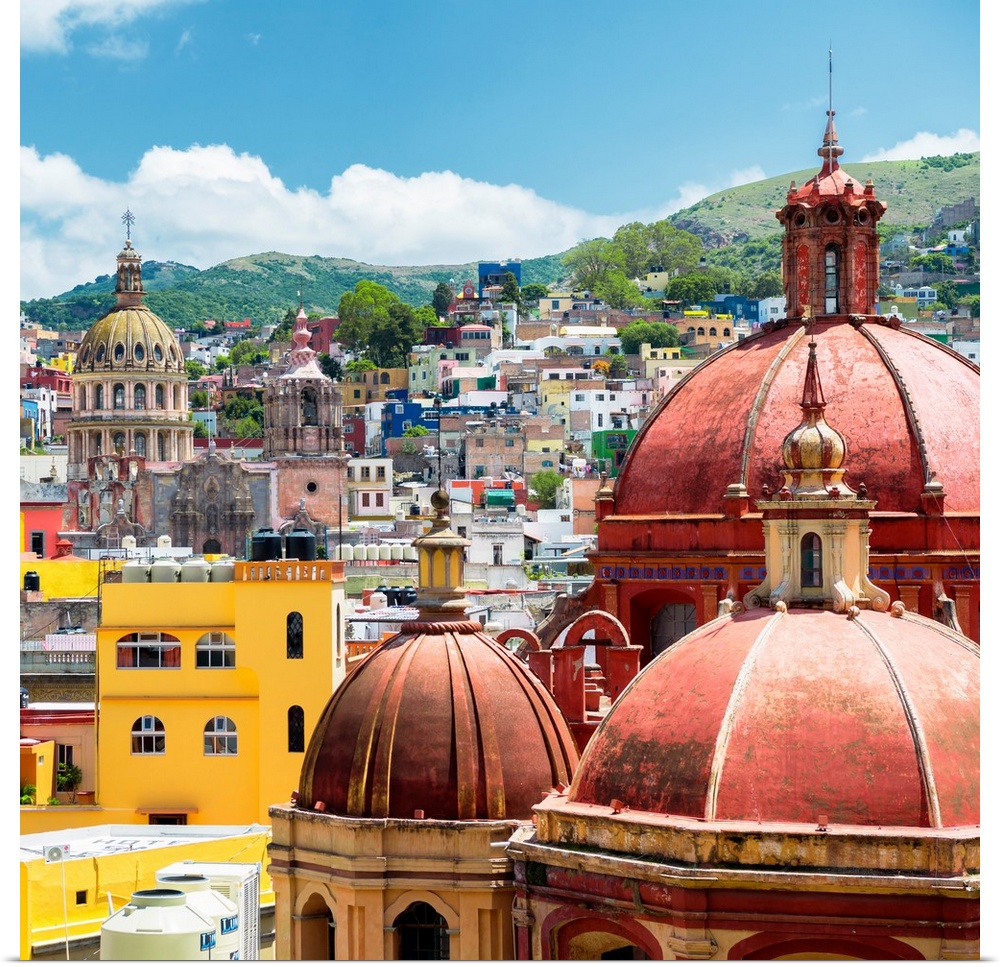 Square photograph of a cityscape in Guanajuato, Mexico, highlighting the colorful buildings and church domes. From the Viv...
