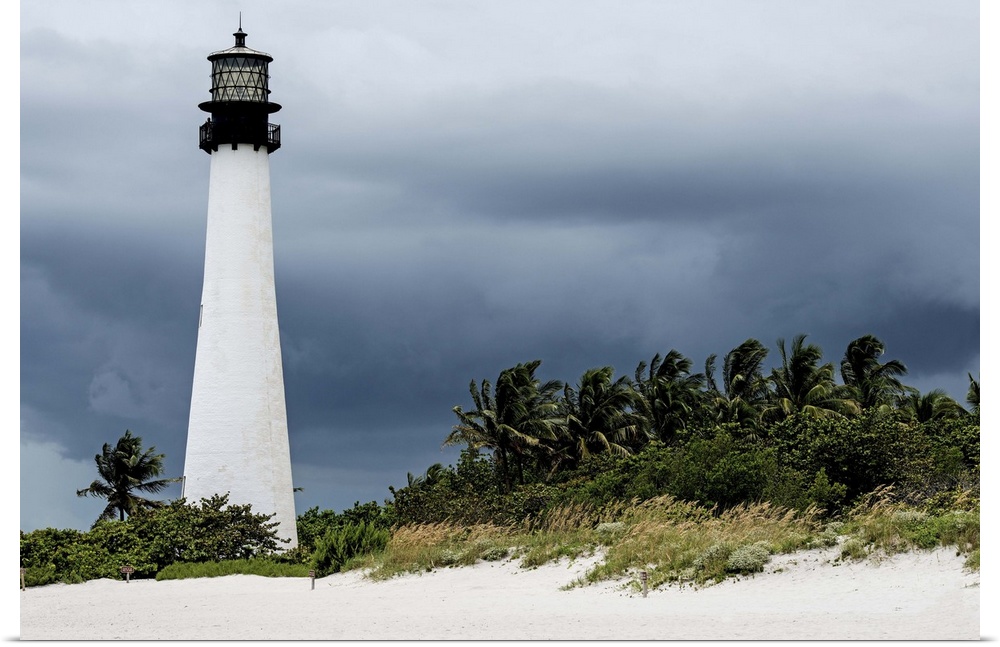 The lighthouse at Key Biscayne towers over the palm trees under a cloudy sky.