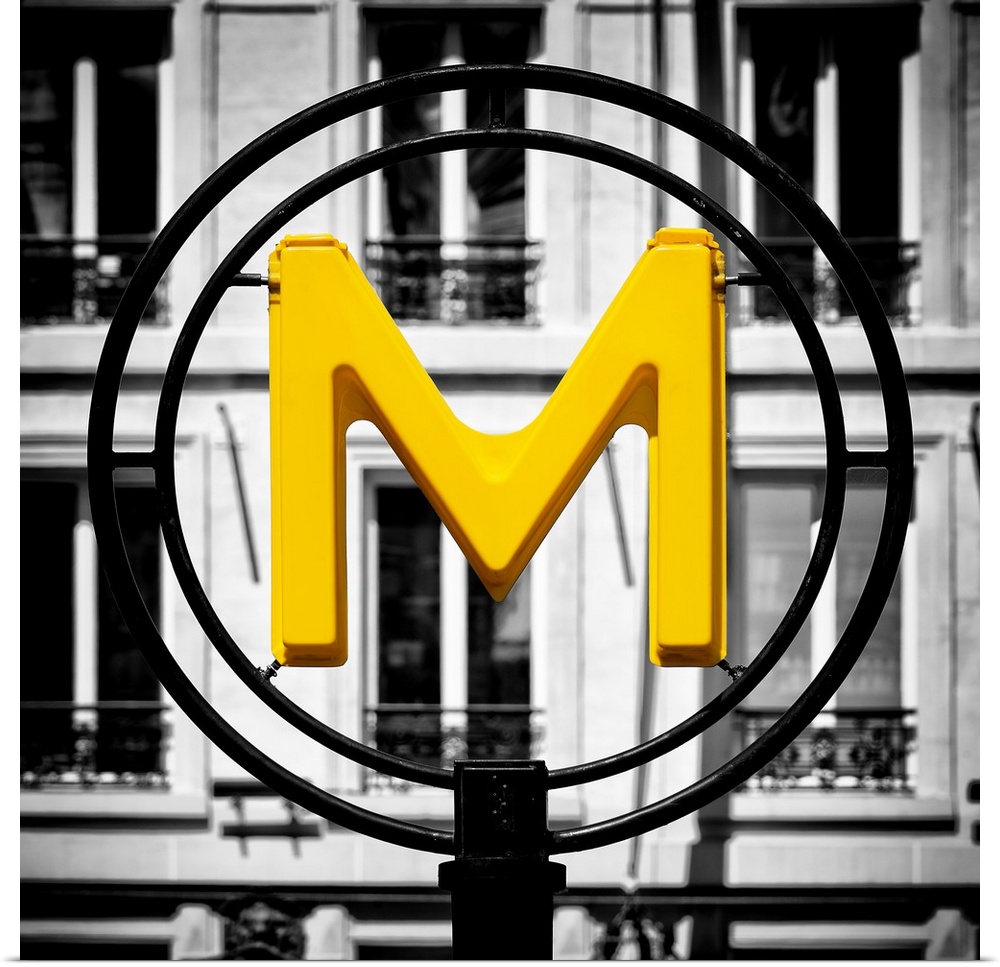 An artistic photograph of a bright yellow M for metro sign against a completely black and white environment.