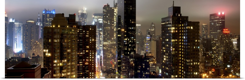 Panoramic photo of the New York city skyline with skyscrapers lit up at night.