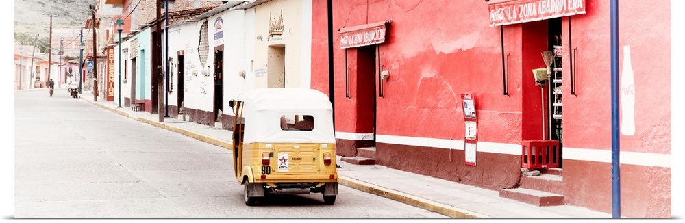Panoramic photograph of a street scene in Mexico with a yellow tuck tuk (taxi) driving up the road. From the Viva Mexico P...