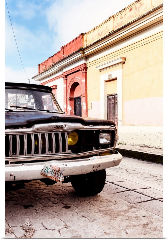 Photograph of a colorful Mexican street with an old black Jeep on the road. From the Viva Mexico Collection.