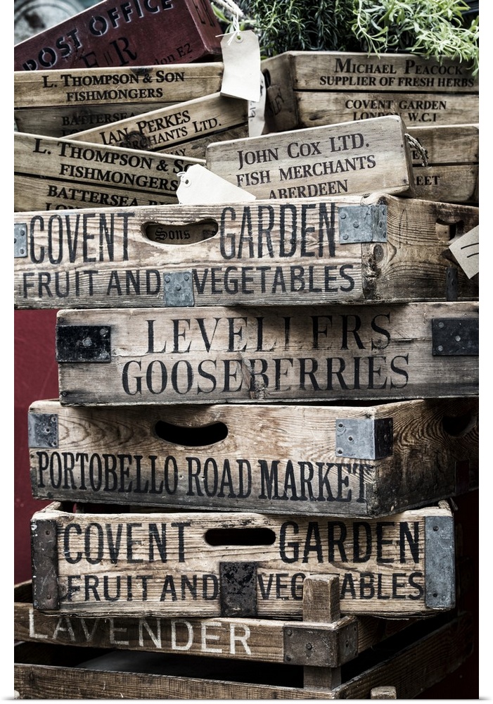 A stack of weathered wooden crates with names of markets lettered on the sides.