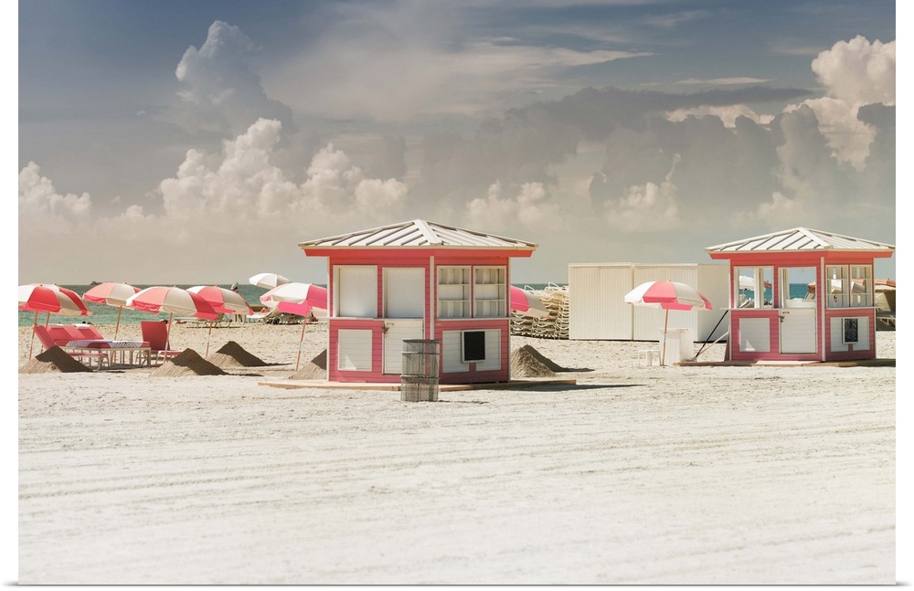Beach huts with matching umbrellas on the sandy beach on a cloudy day.