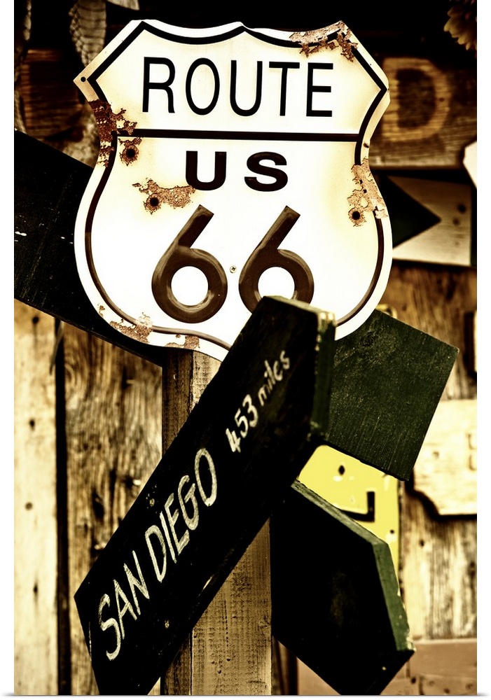 A rusted metal sign for Route 66 and a direction sign pointing towards San Diego.