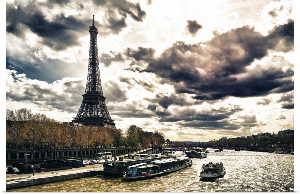 Fine art photo of the Eiffel Tower on the edge of the Seine River with dramatic clouds.