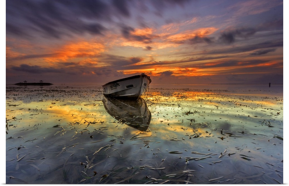 Dramatic sunset over a seascape with a row boat in the foreground.