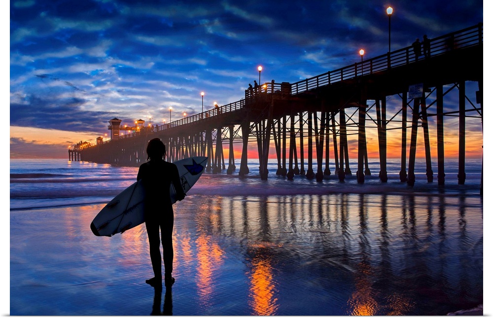 A young surfer takes a moment to linger and admire a colorfully reflective sunset near the Oceanside Pier. Oceanside is 40...