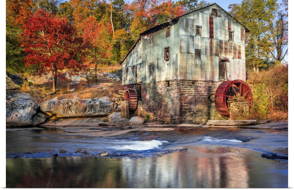 Photograph of a watermill in forest with autumn foliage.