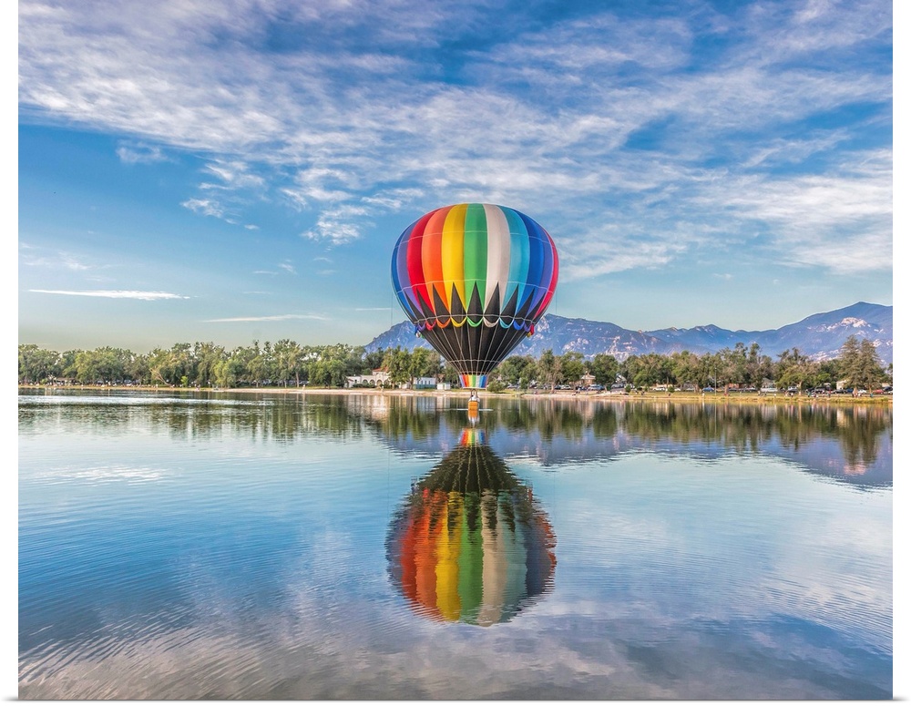 A hot air balloon floating over a lake.