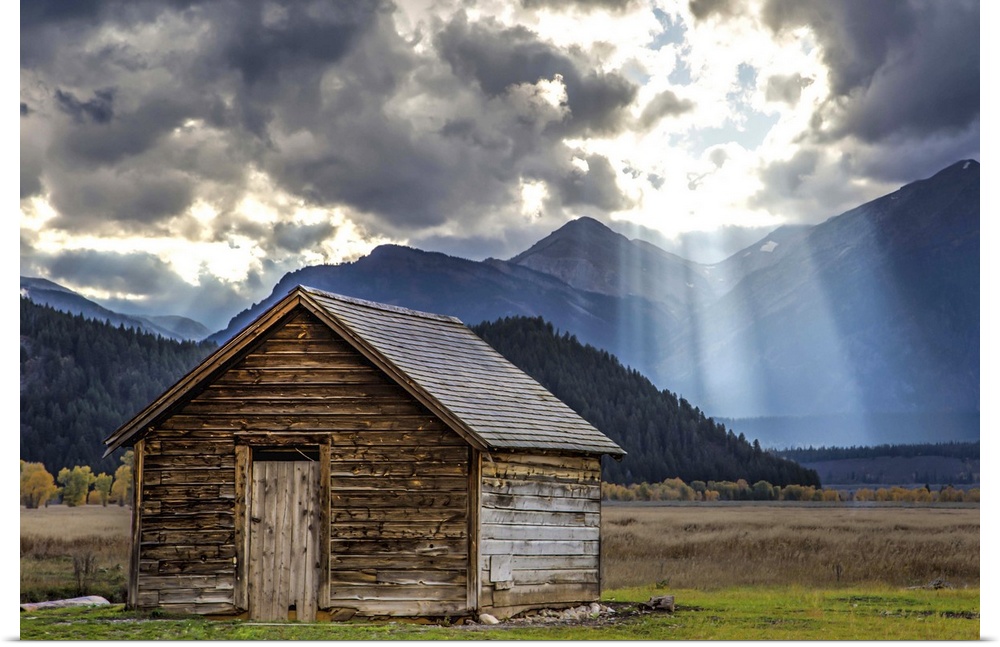 Rays of sunlight shining through the clouds over an old barn in the Grand Teton region, Wyoming.
