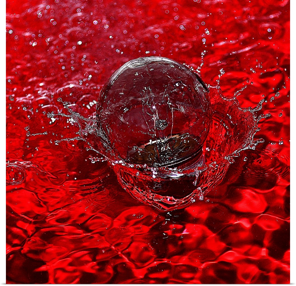 Macro photograph of a water drop splashing into water reflecting bright red.