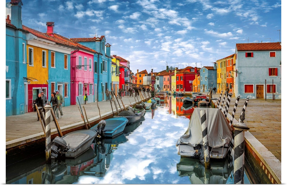 Colorful buildings along the canal reflecting the clouds above, Italy.