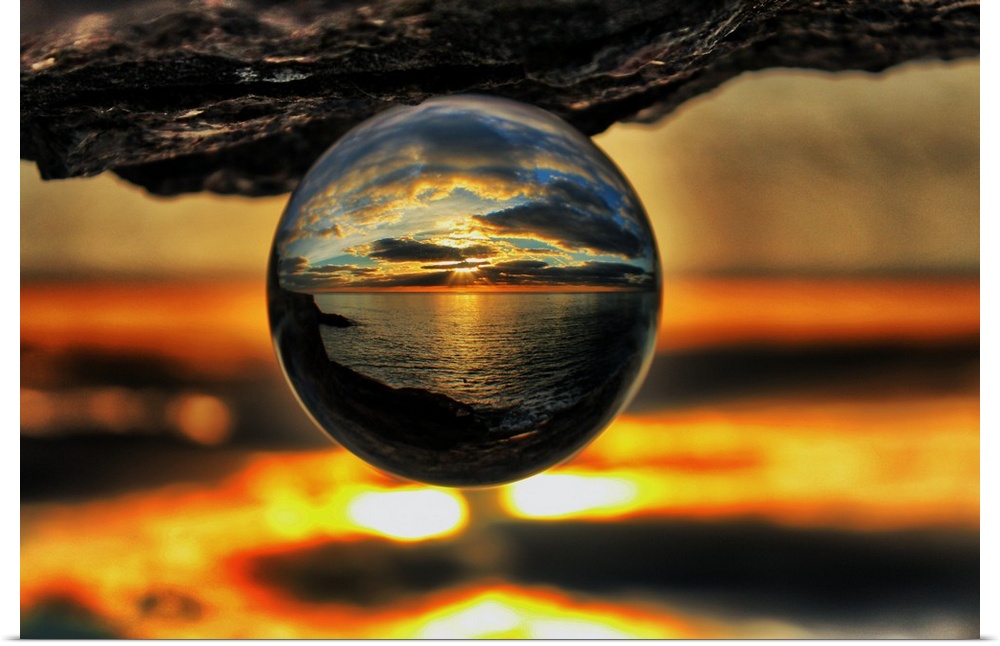 A sunset seascape reflected right-side-up in an upsidedown glass ball.