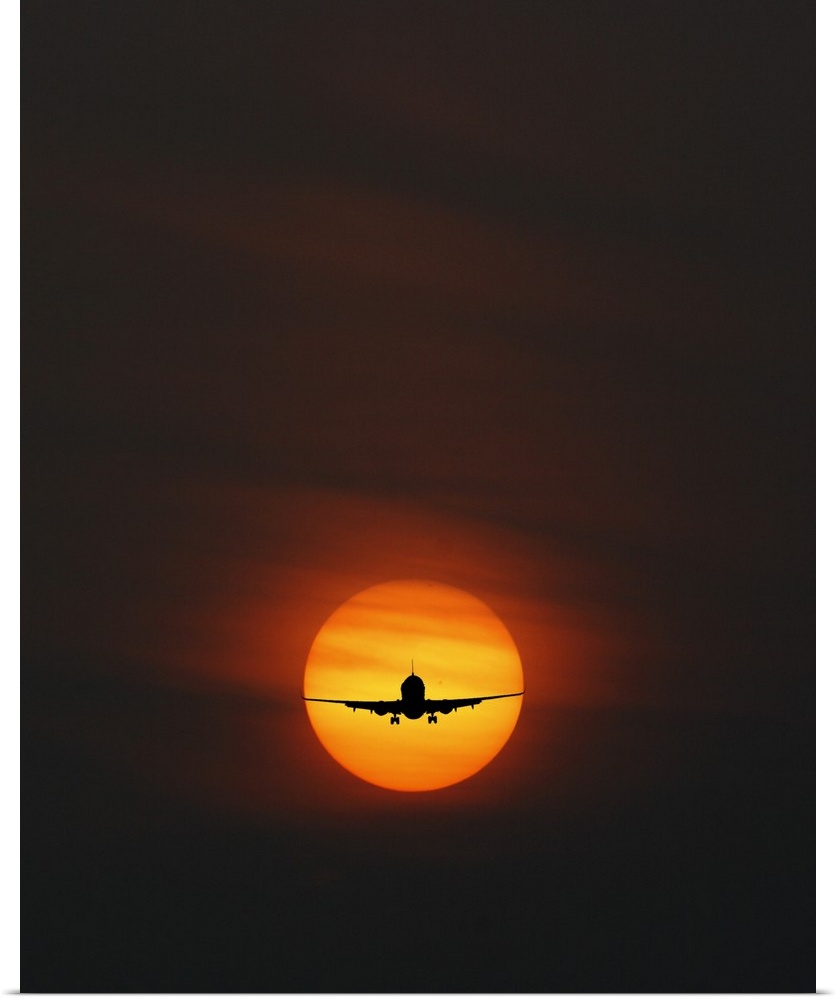 Silhouette of an airplane perfectly framed in the setting sun.