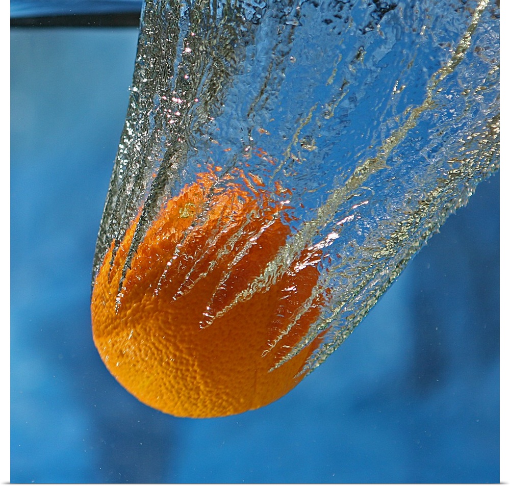 An orange splashing into a tank of clear water.