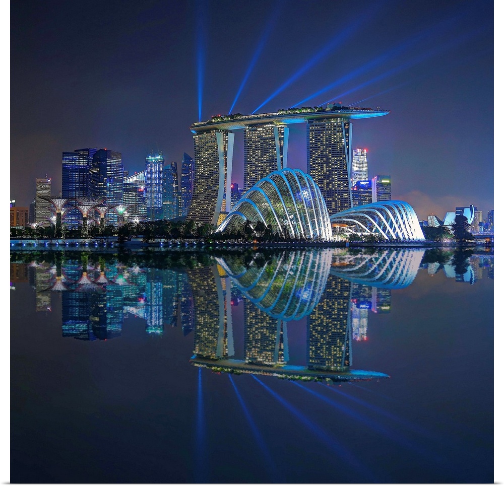 Singapore skyline lit up in neon lights with spot lights stretching out toward the sky.