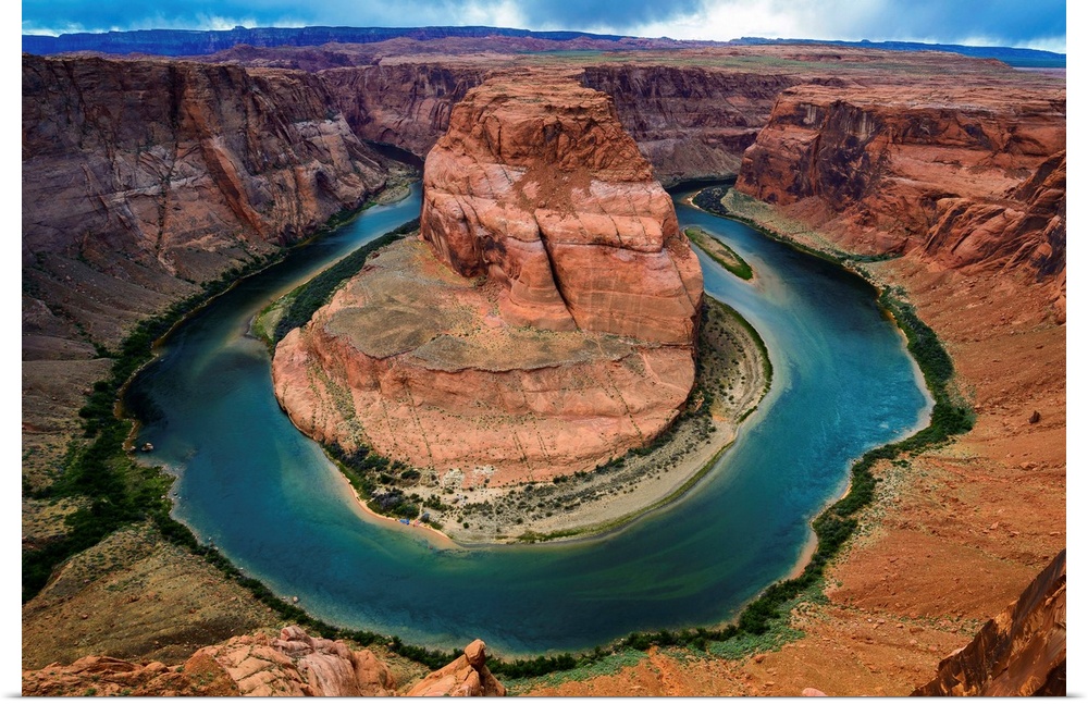 Horseshoe Bend section of the Colorado River with partly cloudy skies and rain in the distance.