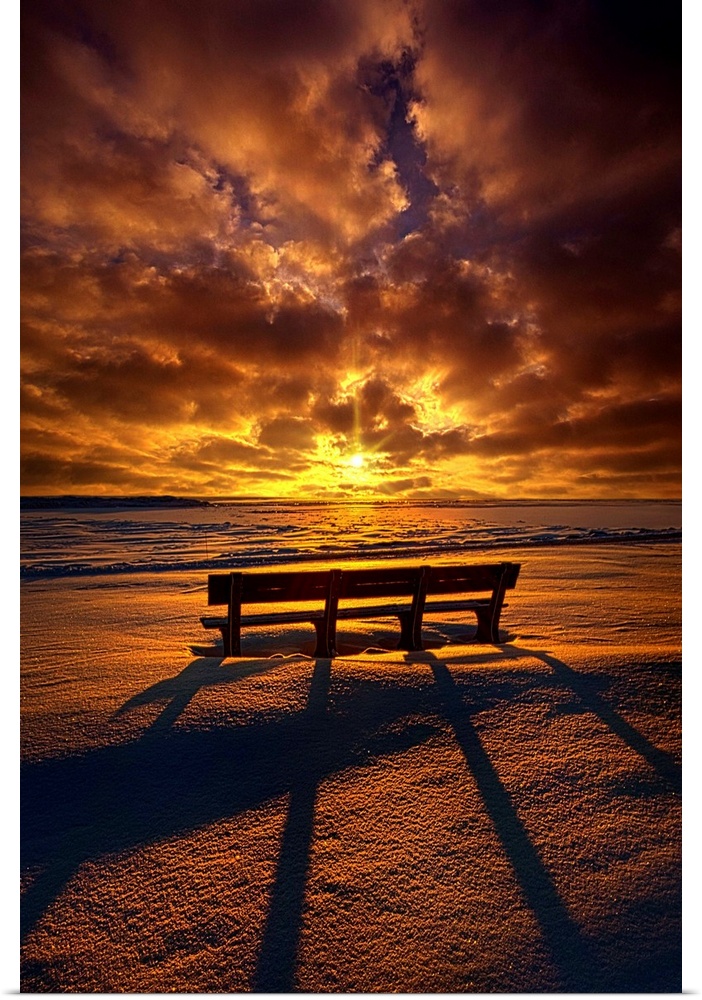 Long shadows cast by a bench at sunset under a cloudy sky.