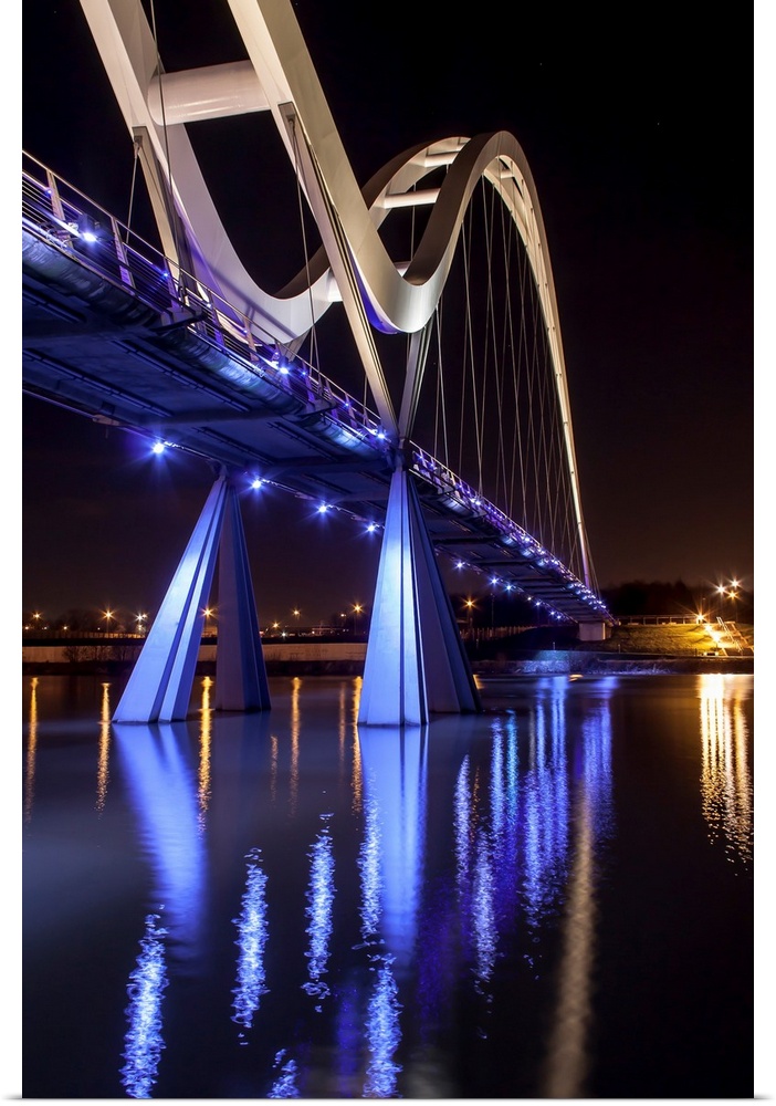 Infinity Bridge with bright blue lights reflected in the water, Stockton on Tees, England.