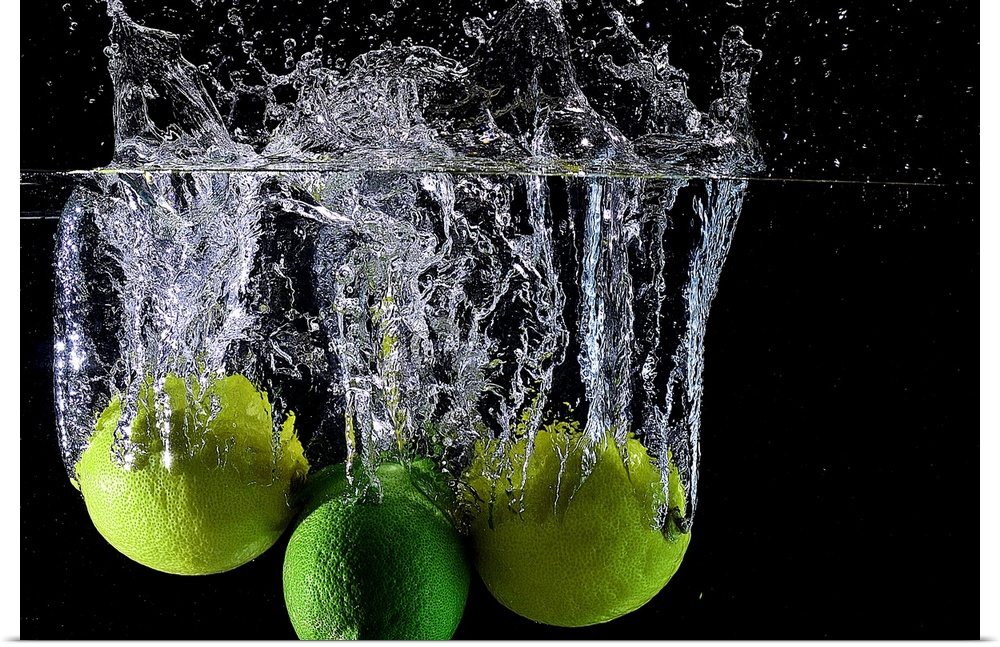 Lemons and limes splashing into clear water.