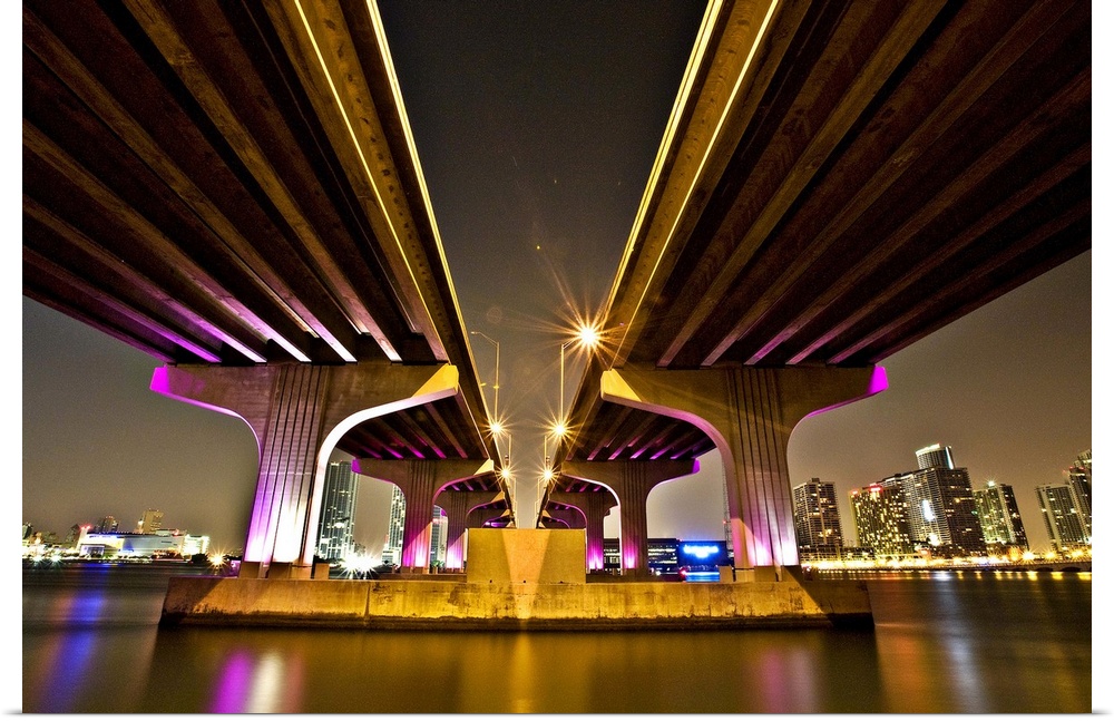 Dynamic photograph of two overpasses leading to Miami, glowing from neon lights.