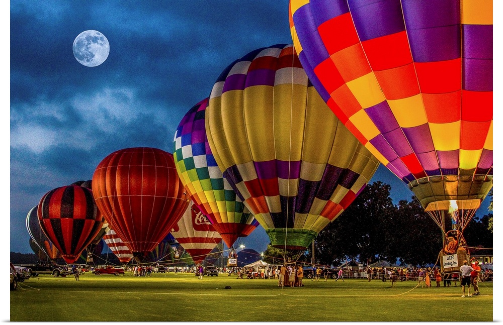 Moon in the night sky over a row of colorful hot air balloons.