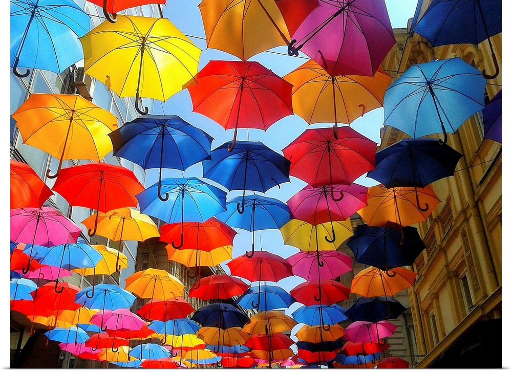 Several colorful umbrellas hanging over a walkway in a street.