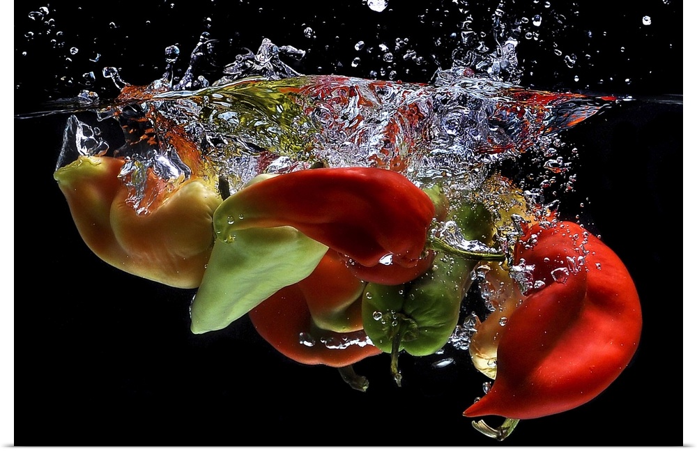 Peppers falling into water, over black background.