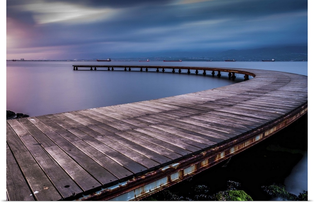 Dynamic photograph of a curved pier jetting out over the water.